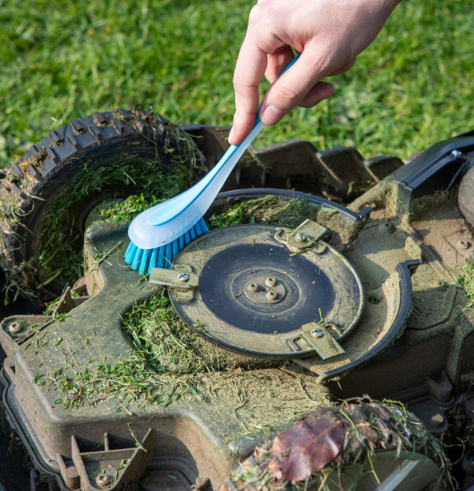 Rasenmäher wird mit Bürste gereinigt